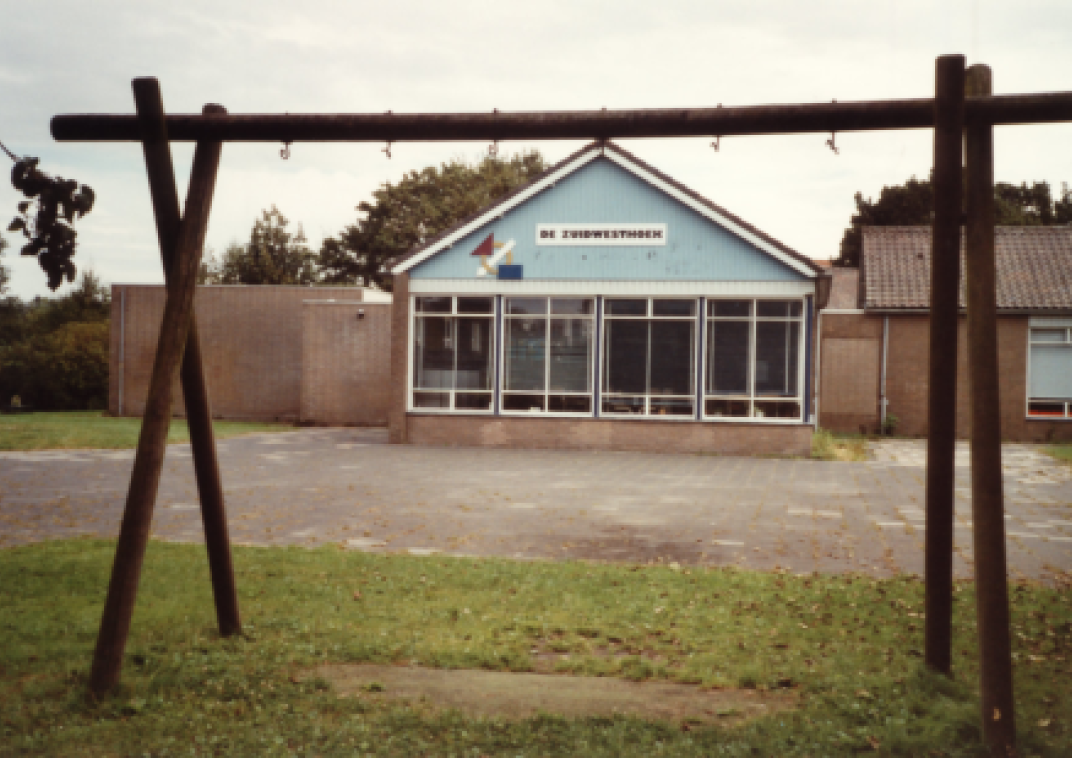 Schoolgebouw met een klein pleintje en een speeltoestel