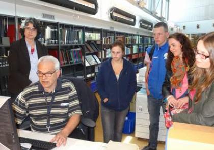 Archiefmedewerker Martin Zuidhof laat de leerlingen en docente (tweede van rechts) zien hoe je oude kaarten van Goes in een database opzoekt