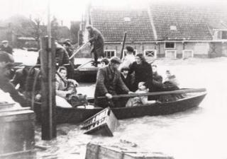 Foto van een overstroomd gebied met mensen die in een bootje vervoerd worden