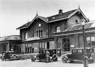 Het oude stationsgebouw van Goes, met 3 auto's geparkeerd voor het gebouw