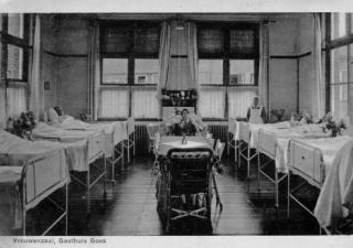 Vrouwenzaal in het ziekenhuis. Aan beide kanten van de ruimte zijn vier bedden te zien, en één staat tegen de achtermuur.