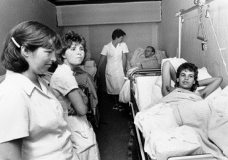Een wagen met patiënten in bedden en verplegers die erbij staan