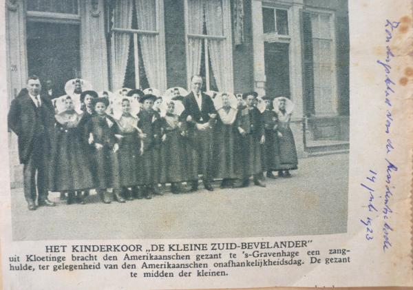 Krantknipsel met foto van kinderkoor. Een groep kinderen staat voor een gebouw. 