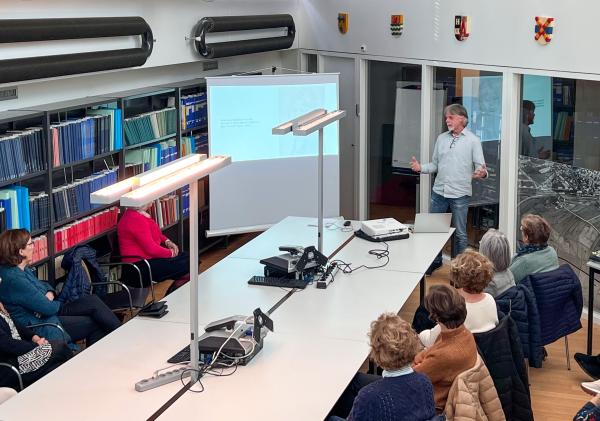 Frank de Klerk presenteert een lezing voor een groep vrouwen in de studiezaal.