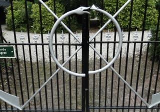 Ouroboros en twee zeisen op het hek van de begraafplaats