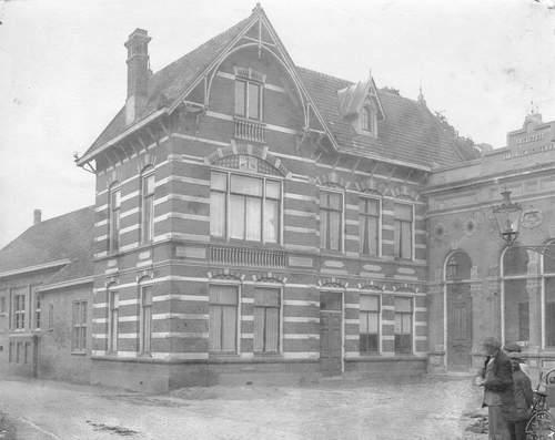 Een gebouw met rechtsonder in de hoek drie mensen