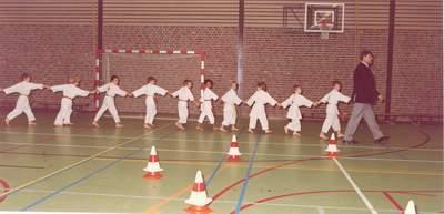 Rij van kinderen in judo-pakken die hand-aan-hand achter Anton Geesink aanlopen