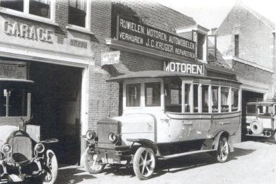 winkel met verschillende teksten op op borden zoals "Motoren" en "Rijwielen. Motoren. Automobielen verhuren" en een auto ervoor