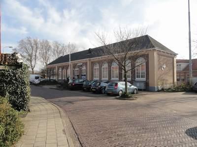 Dorpshuis van een afstandje, een rij auto staat ervoor geparkeerd