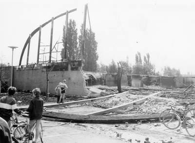Mensen kijken op afstand naar het afgebrande gebouw