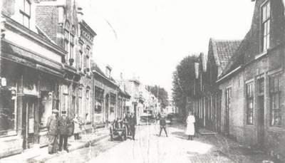 Straat met huizen aan beide zijden, en mensen die stilstaan of rondlopen