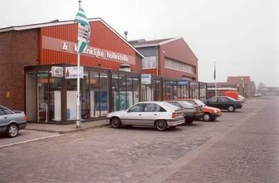 Twee winkels met een rij auto's ervoor geparkeerd
