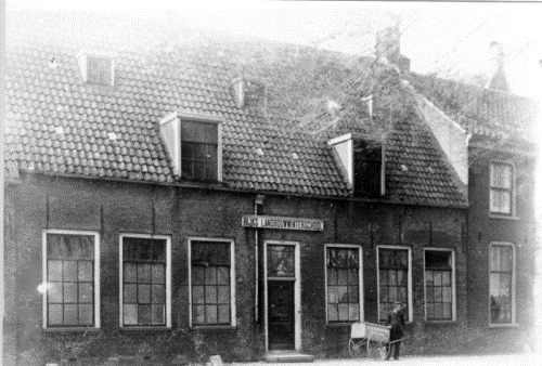 Rijkslandbouwwinterschool. Er staat iemand voor het gebouw met een kar op twee wielen