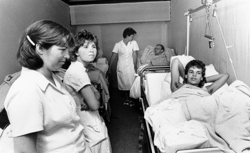 Een wagen met patiënten in bedden en verplegers die erbij staan