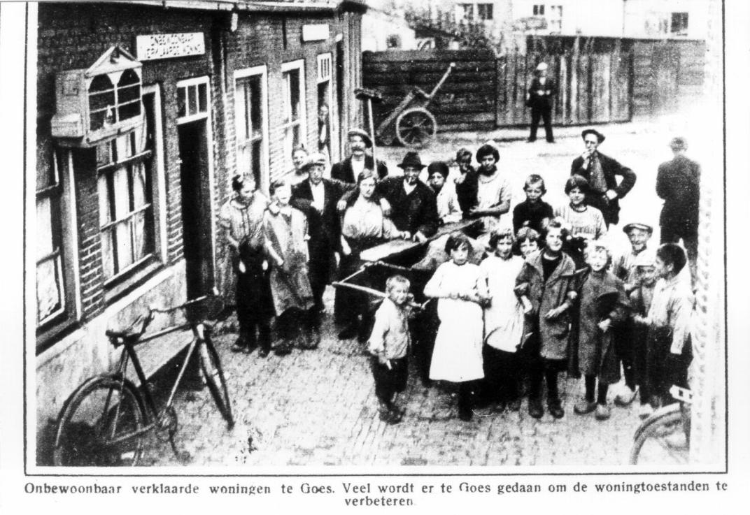 Een grote groep mensen staat buiten op straat, ze kijken allemaal in de camera