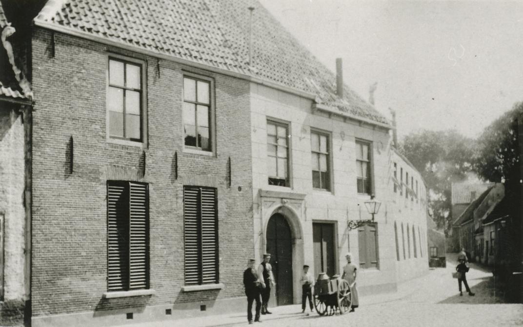 Het oude gasthuis, waar een aantal mensen geposeerd staat bij de ingang