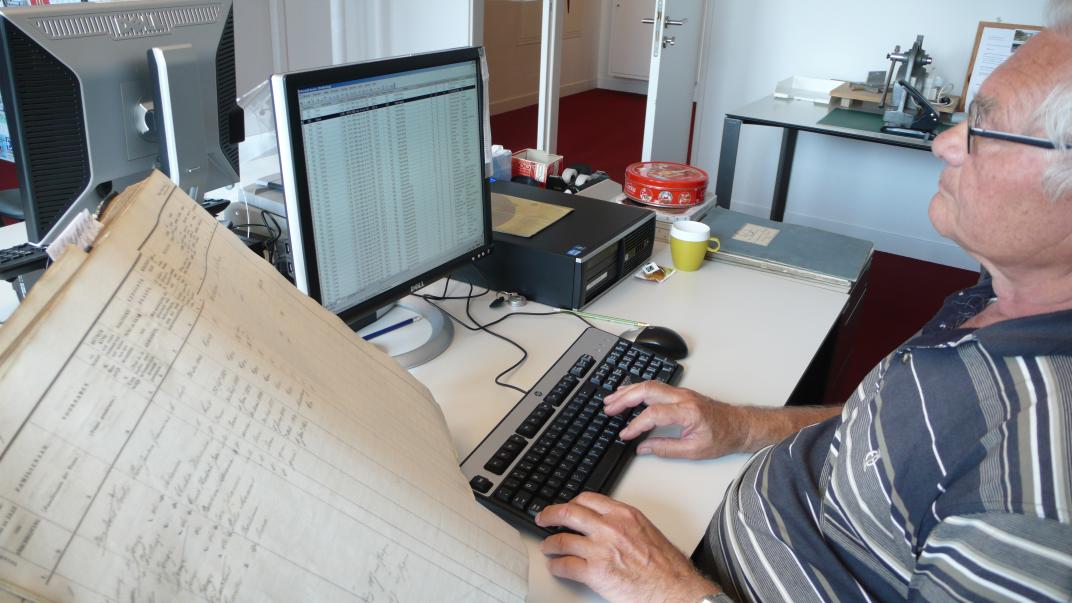 Huub Bellaart typt gegevens uit een bevolkingsregister over