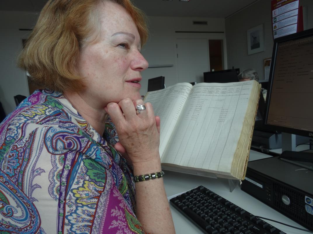 Corrie zit achter een computer met een bevolkingsregister voor haar