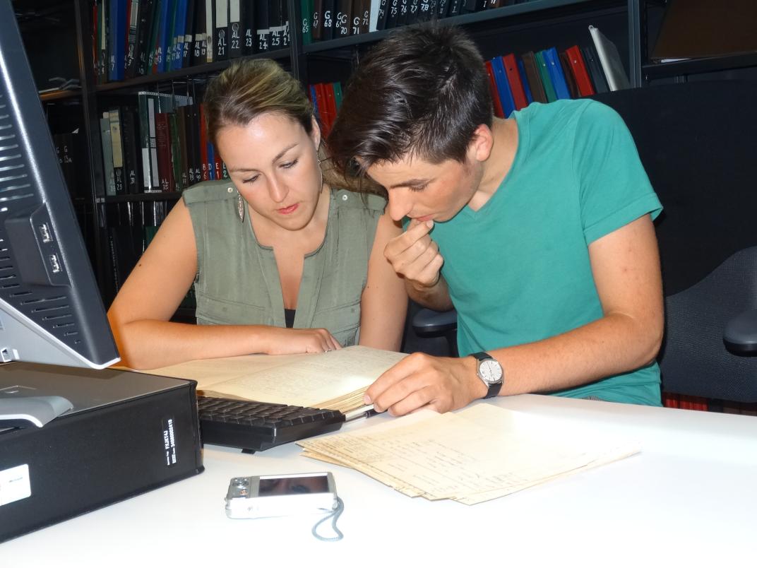 Sharon en Remi Gunther zitten achter een computer in de studiezaal en kijken in een boek