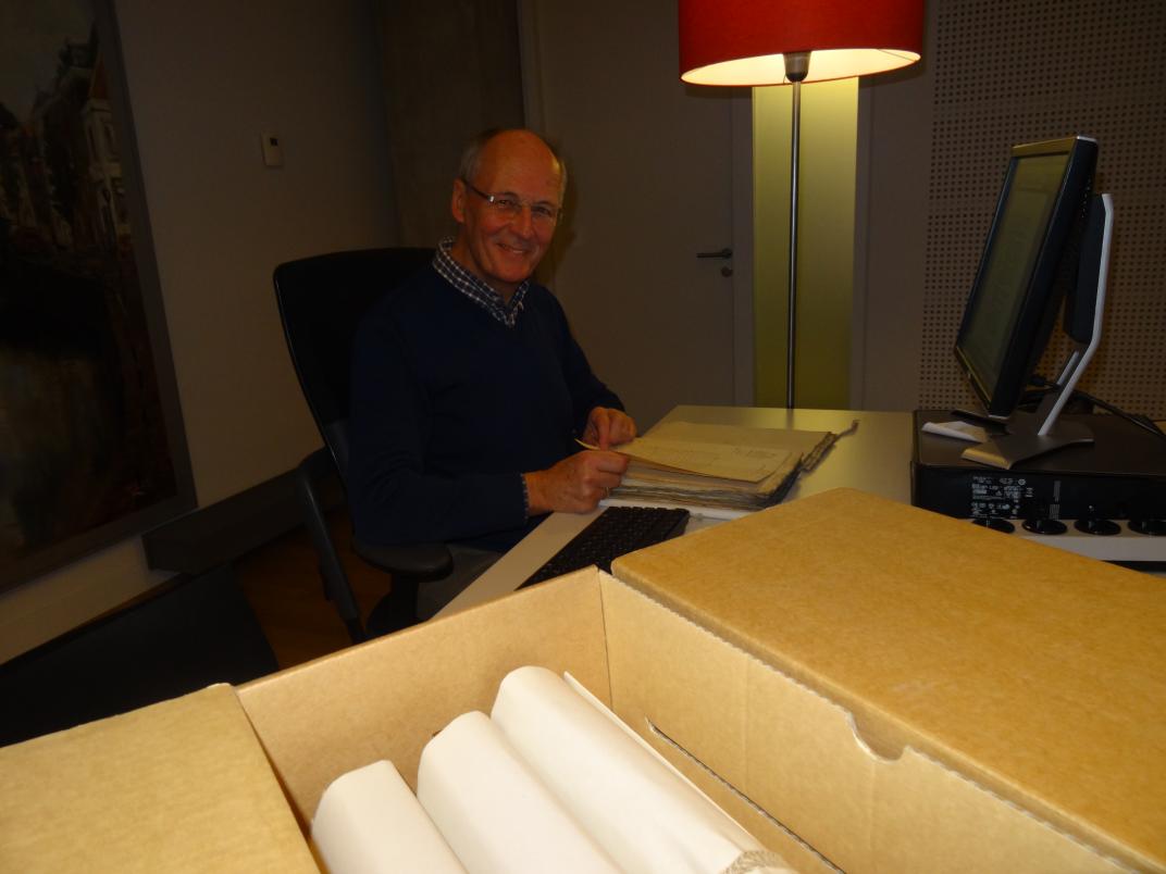 Joost Adriaanse in de raadsledenkamer, bezig aan zijn onderzoek