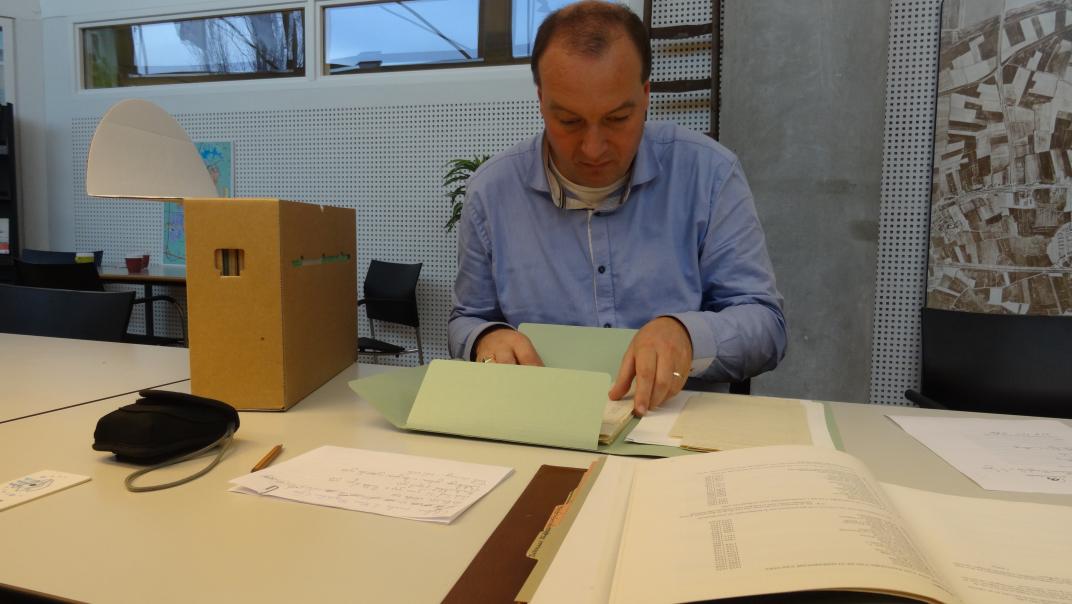 André van Noort zit aan een tafel met archiefstukken in de studiezaal