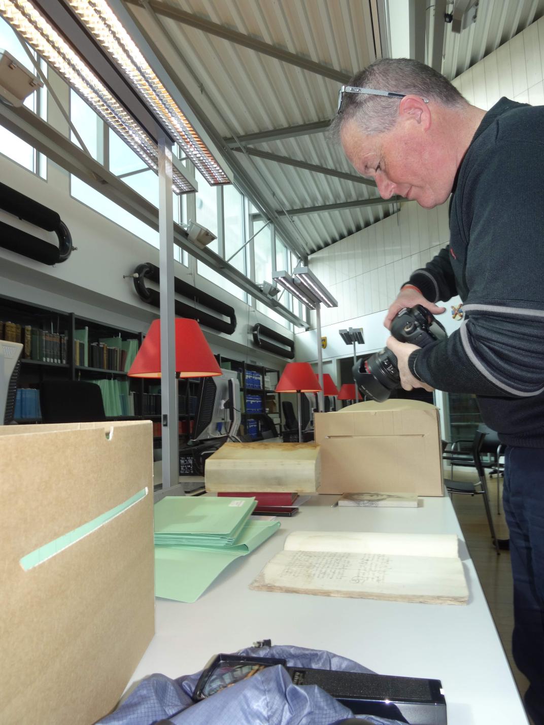 Henk de Kunder maakt foto's van een archiefstuk