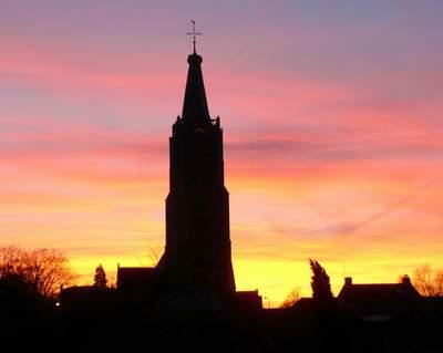 Silhouet van de Geerteskerk tegen een zonsopgang of ondergang