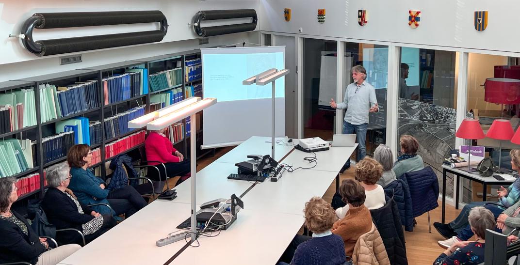 Frank de Klerk presenteert een lezing voor een groep vrouwen in de studiezaal.