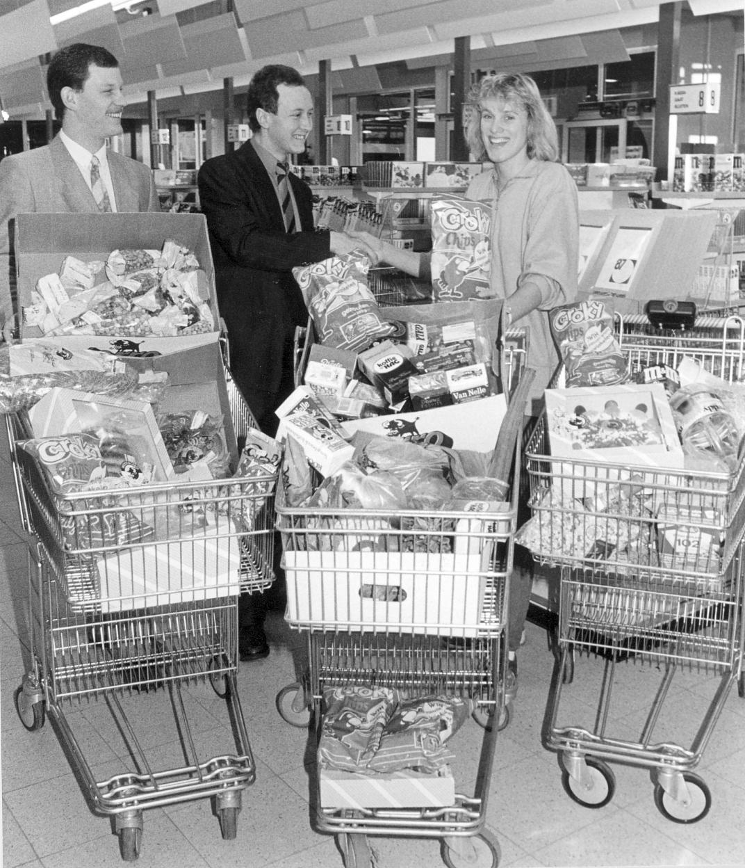 3 mensen achter 3 winkelwagens gevuld met boodschappen