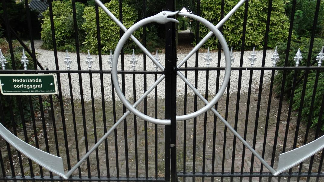 Ouroboros en twee zeisen op het hek van de begraafplaats