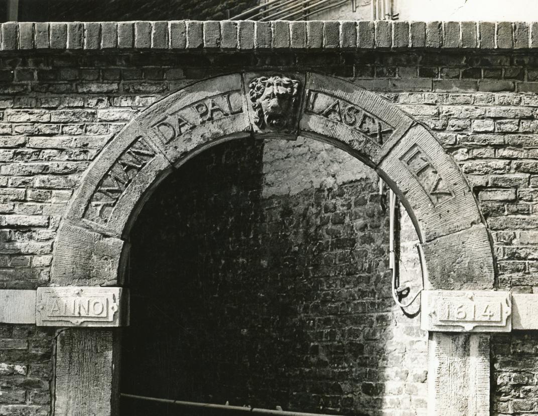 Fragment poortje van de voormalige Latijnse school aan de Kreukelmarkt. Het poortje is gedateerd anno 1614, met een leeuwenmasker als sluitsteen. Het opschrift op de rondboog: AMANDA PALLAS EXITU (vertaling: ‘Zij die oefenen worden door Pallas bemind’. Pallas is godin van de wijsheid en wetenschap).